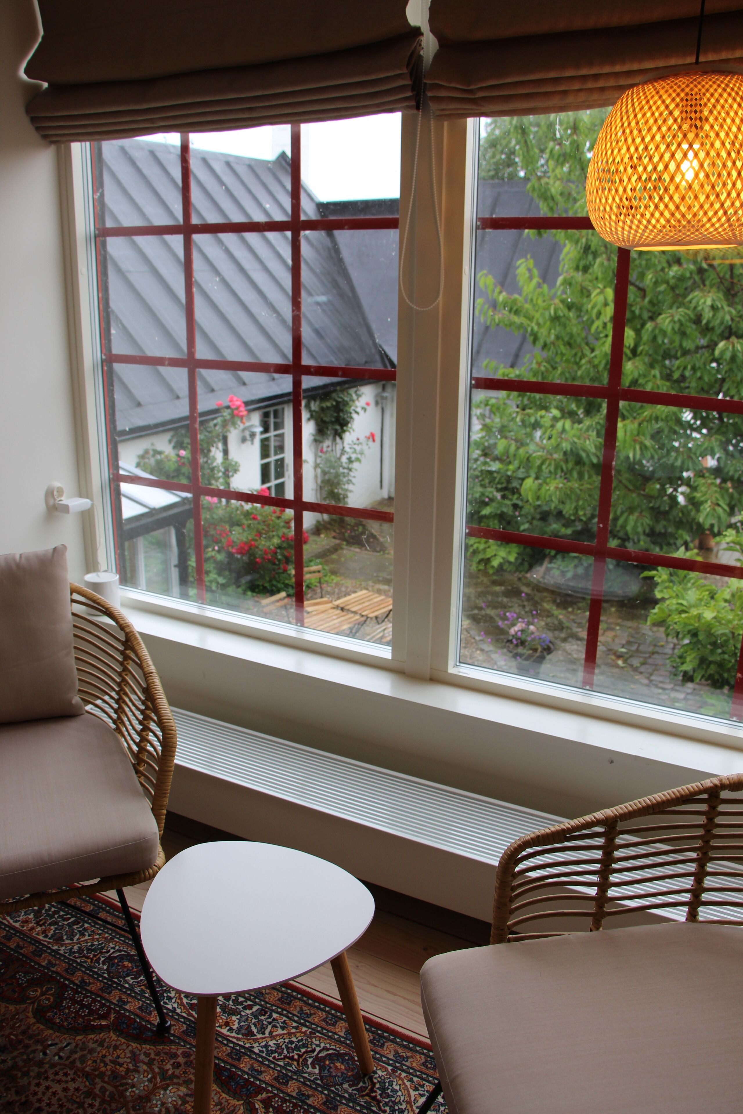 A room with a large window, wicker furniture, and a hanging light fixture.