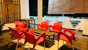 A dining area with red chairs and a wooden table, large windows with a view, and a decorative wooden panel on the wall. - Happy Resort Yala (Thissamaharama)