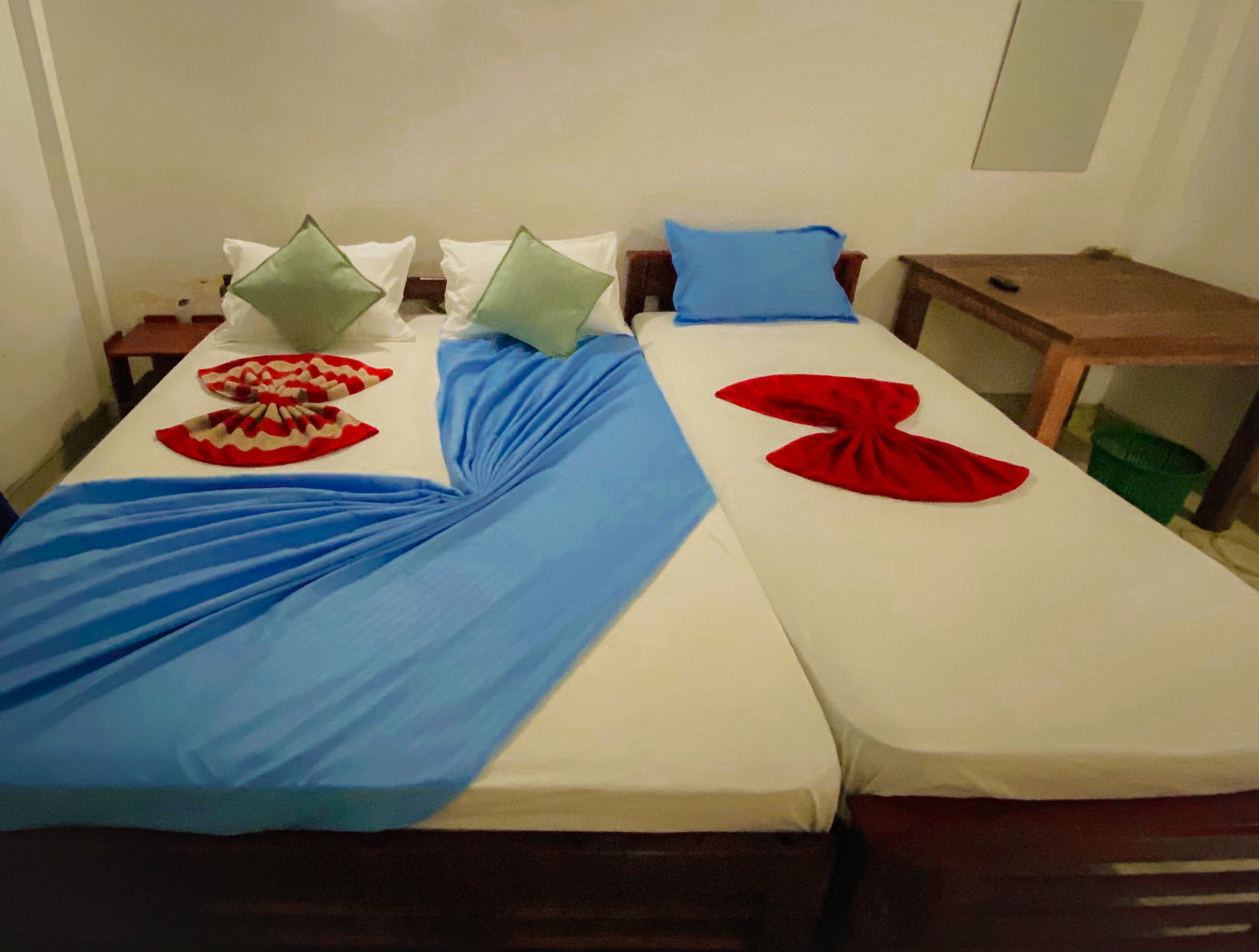 A double bed with blue and red towels arranged on the bed.