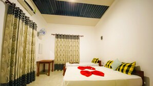 A hotel room with two beds, a ceiling fan, and a window with curtains. - Happy Resort Yala (Thissamaharama)
