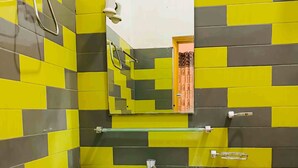 A bathroom with a white sink, yellow and gray tiles, a mirror, and a towel rack. - Happy Resort Yala (Thissamaharama)