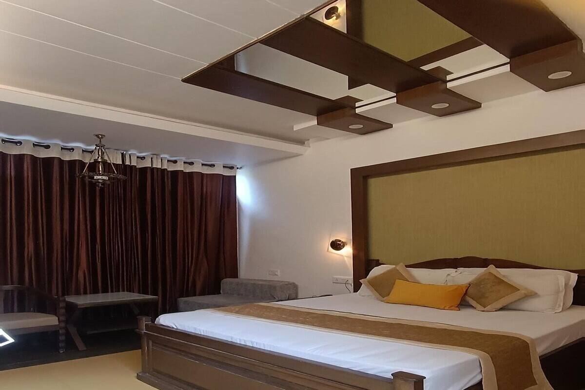 A hotel room with a large bed, a desk, a chair, and a chandelier.