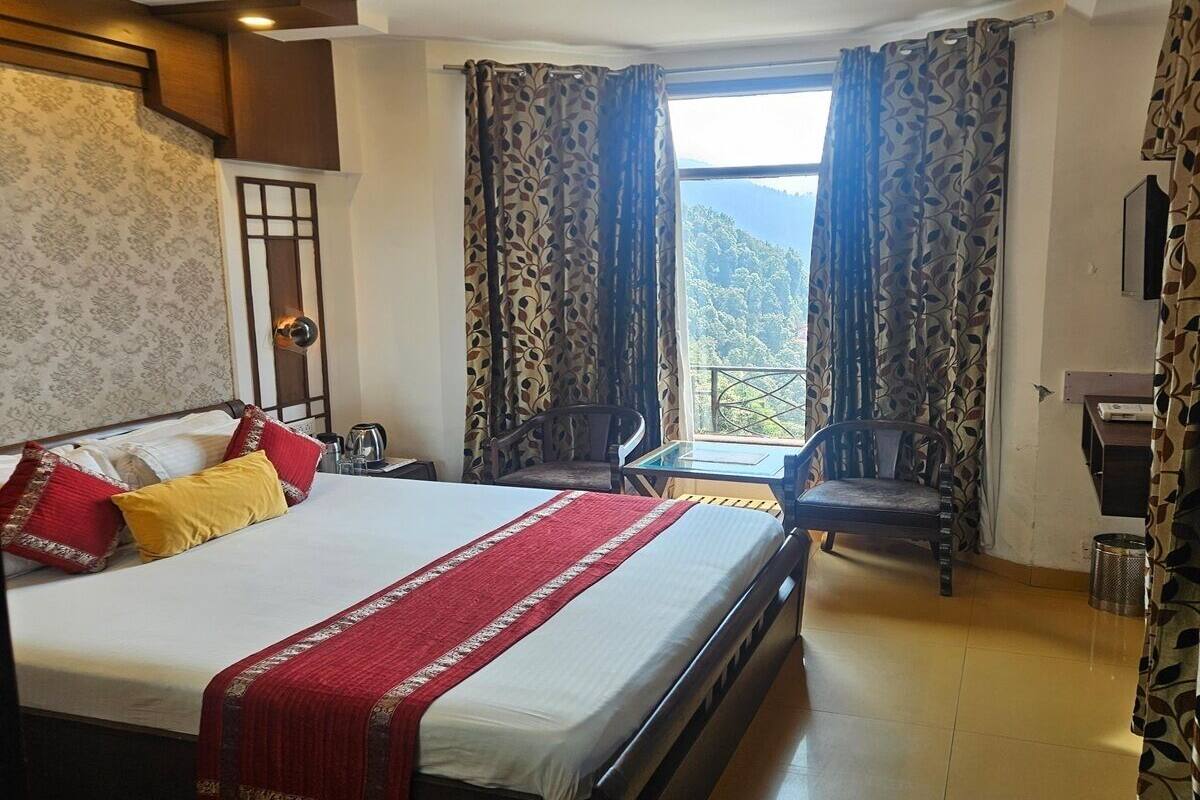 A hotel room with a large bed, a desk, a chair, and a view of the outdoors.