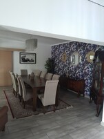 Un comedor con una mesa y sillas de madera, una araña y un diseño de papel tapiz floral.