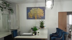 Een moderne keuken met een centraal eiland, een schilderij van een boom en een blauw gestreepte stoel.
