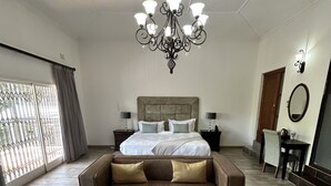 Een ruime slaapkamer met een groot bed, een kroonluchter, een bank en een bureau.