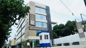 Un hotel moderno con varios pisos, una entrada destacada y señalización que indica servicios como habitaciones, banquetes y baños.
