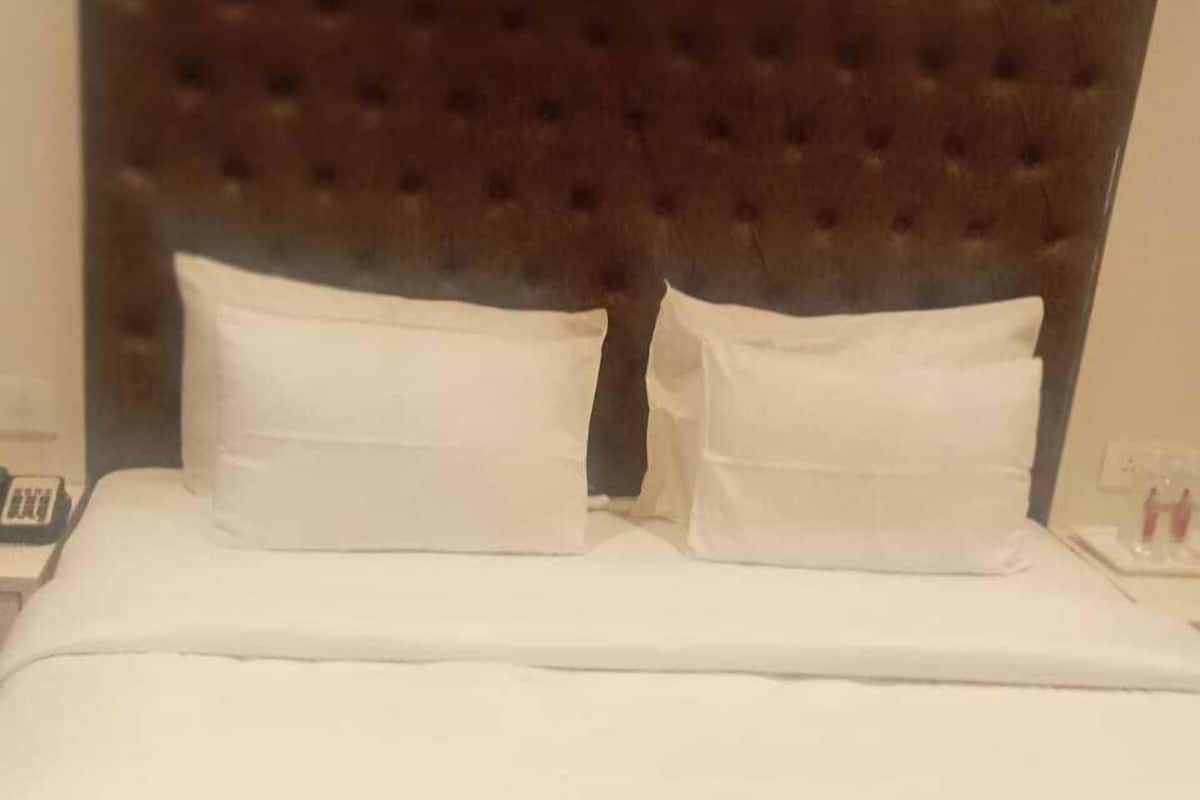 Un llit ben fet amb llençols blancs i un capçal amb borrons.