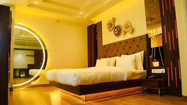 Un dormitorio moderno con una cama grande, un espejo circular y suelo de madera.