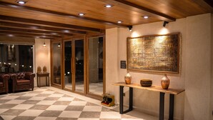 A hotel lobby with a checkered floor, wooden ceiling, and a large decorative wall piece. - The Sarai (Srinagar)