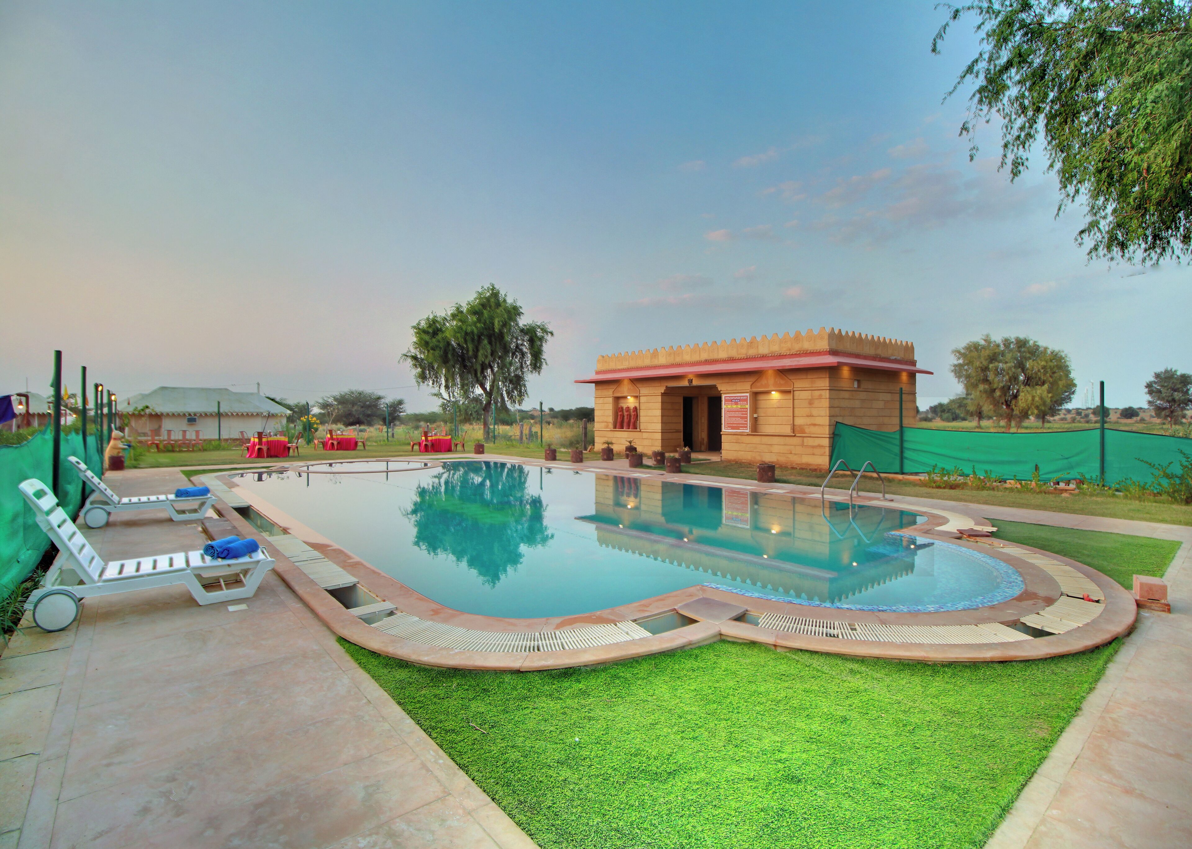 A swimming pool with lounge chairs and a small building with a red roof.