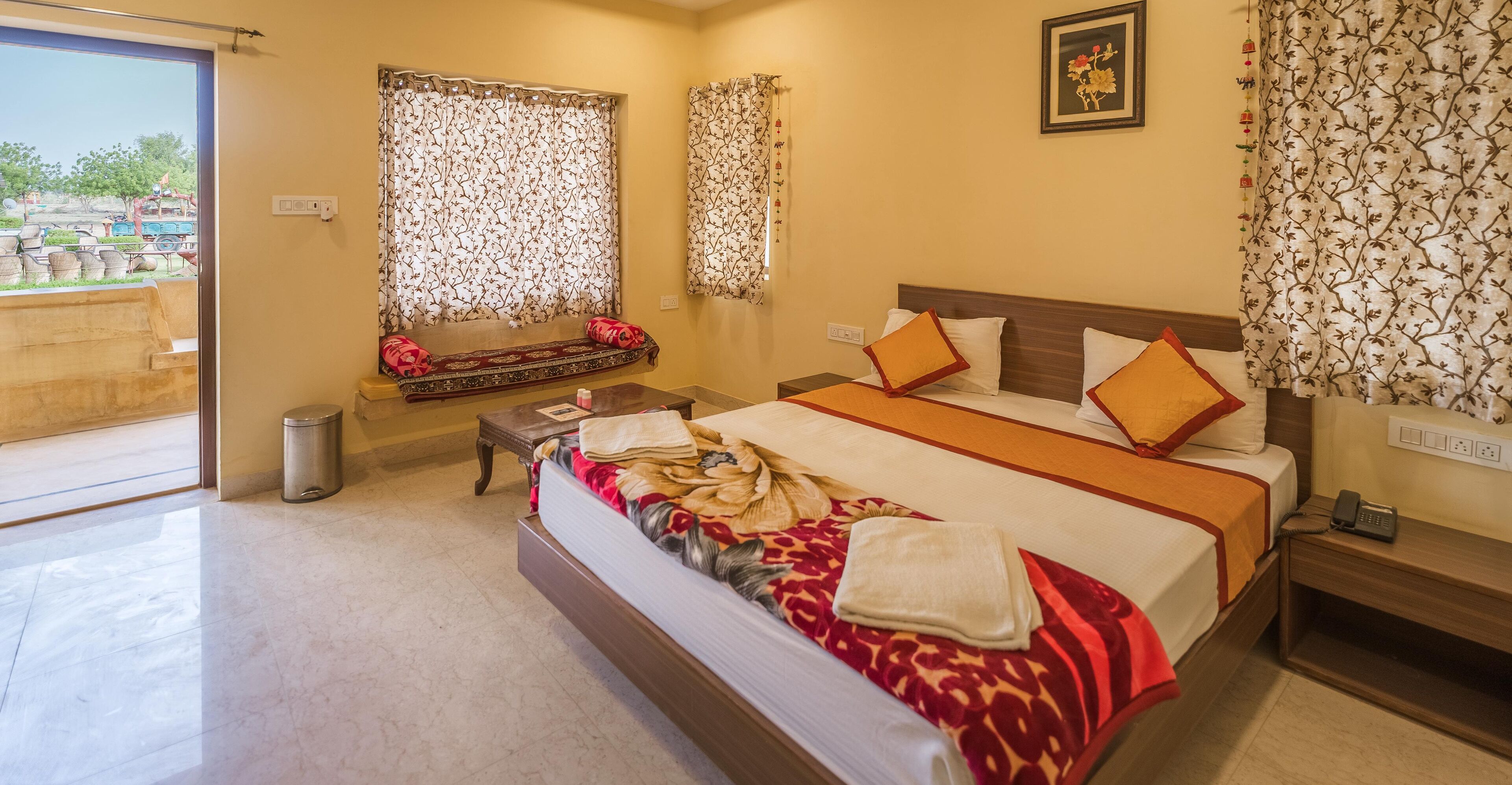A hotel room with a bed, bedside table, and a window with curtains.