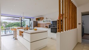Una cocina moderna con una isla central, electrodomésticos integrados y vistas al exterior.