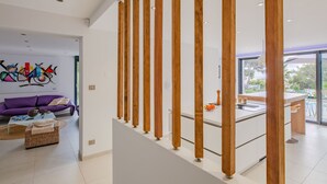Un interior moderno con un separador de madera, un sofá morado y un comedor con vistas.