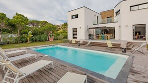 Una casa moderna con piscina, mobiliario exterior y zona de patio.