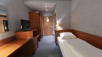 Una habitación de hotel con cama, escritorio, televisor y armario.