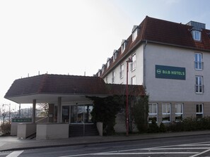 Un hotel B&B con una entrada cubierta y una escalera que conduce a ella, bajo un cielo despejado.