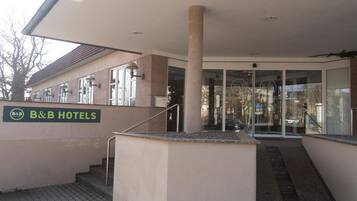 Les hôtels B&B se distinguent par leur façade sobre, une entrée clairement identifiable, un escalier menant à l’entrée et une enseigne bien visible.