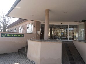 The exterior of B&B Hotels with a clear entrance, a staircase leading to the entrance, and a visible signboard.