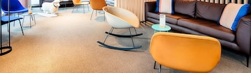 Una sala de estar moderna con un sofá de cuero marrón, sillones naranjas y una mecedora blanca.