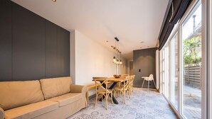 Un salon moderne avec un canapé beige, une table à manger avec des chaises et un sol à motifs.