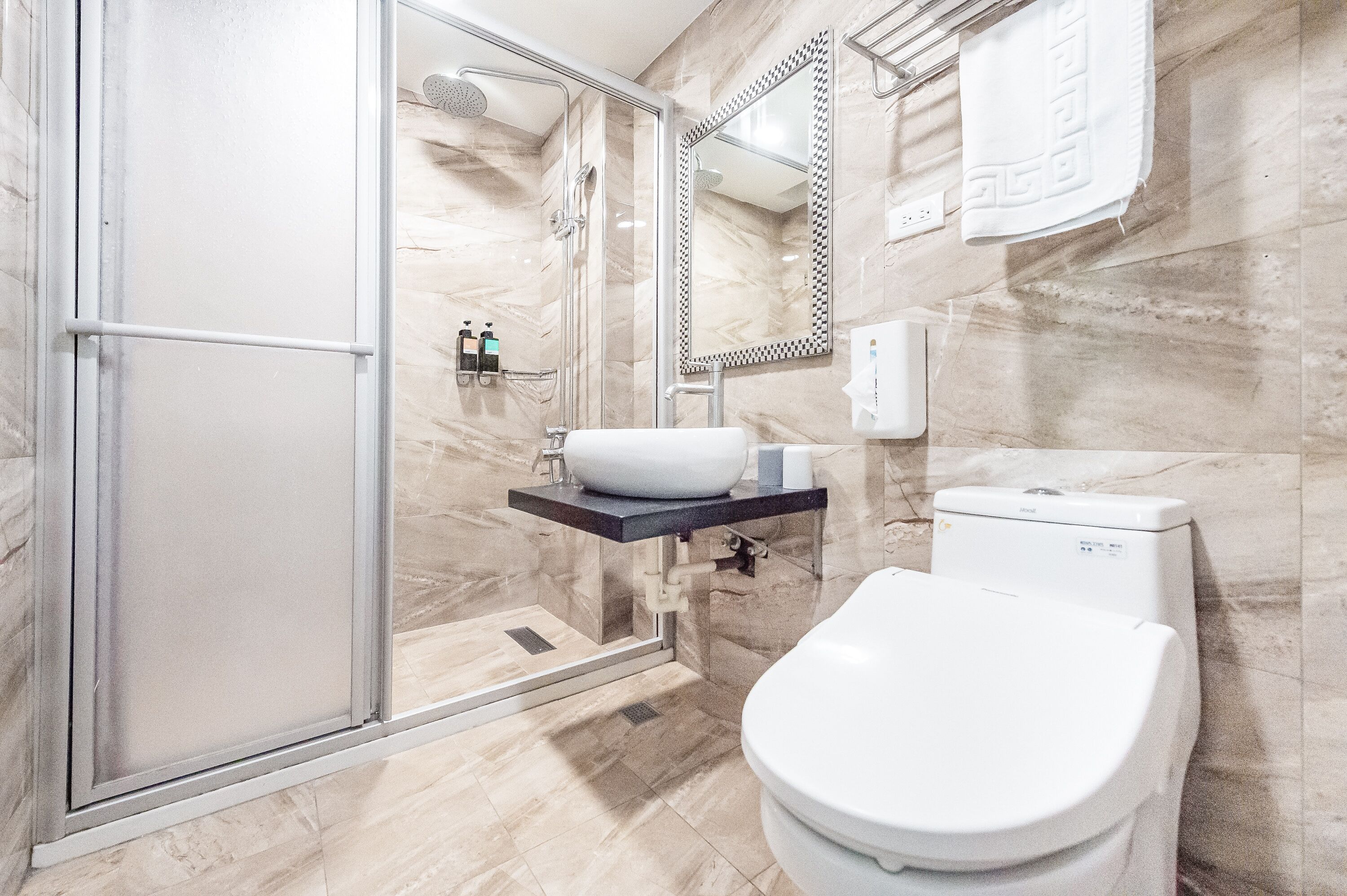 Een moderne badkamer met een douchecabine van glas, een wit wastafelmeubel en een toilet.