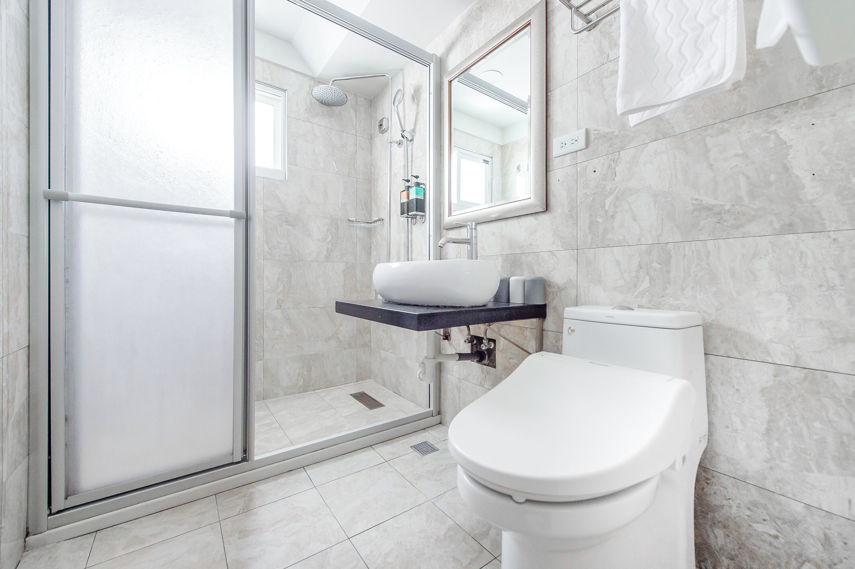 Un bagno moderno con doccia vetrata, un WC bianco e un pavimento in marmo.