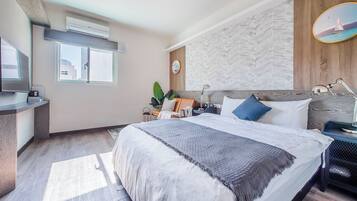 Een moderne hotelkamer met een groot bed, een bureau, een stoel, een televisie en een raam met uitzicht op gebouwen.