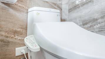 A modern toilet with a control panel and a flush button.