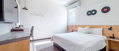 A modern bedroom with a bed, bedside tables, a mirror, and a wardrobe.
