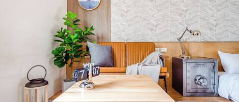 A modern room with a wooden sofa, a small table, a potted plant, a metal lantern, and a safe.