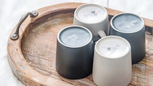 Quatre tasses en céramique sur un plateau en bois doté d’une anse en métal.