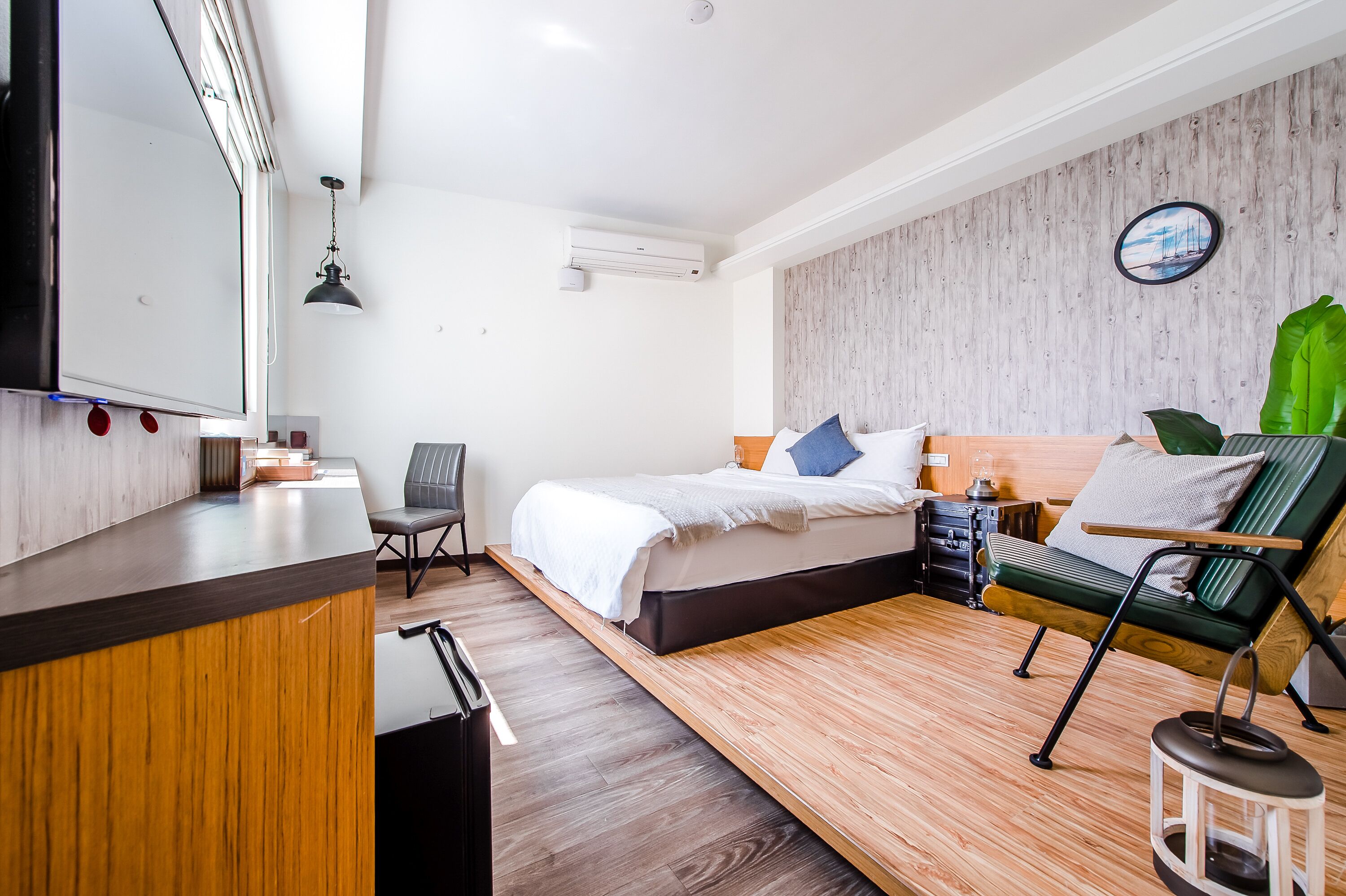 A modern hotel room with a bed, a desk, a chair, and a small table.