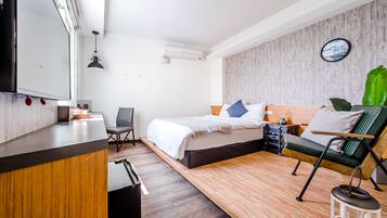 A modern hotel room with a bed, a desk, a chair, and a small table.