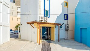 Un bâtiment blanc avec une bande verticale bleue et une porte rouge.