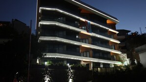 Un immeuble à plusieurs étages doté de balcons et d’un éclairage extérieur décoratif.
