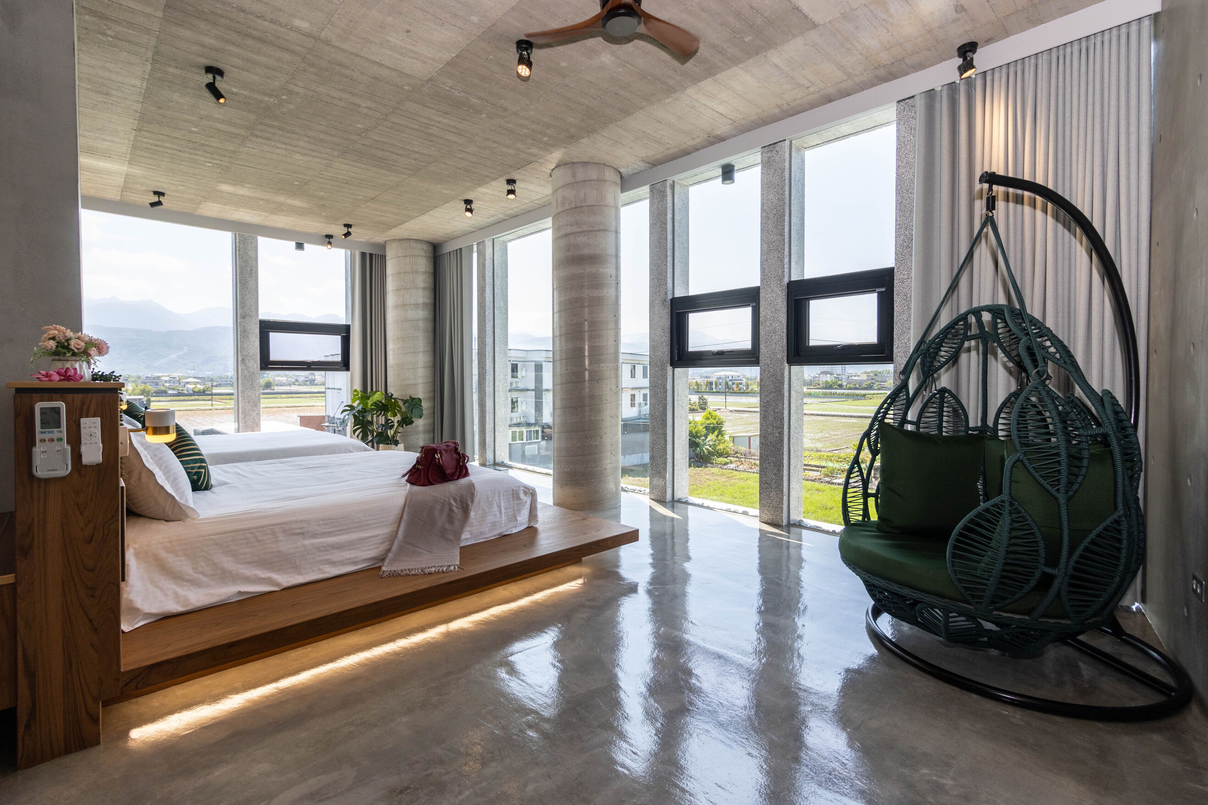 A spacious bedroom with a large bed, a hanging chair, and a view of the outdoors.