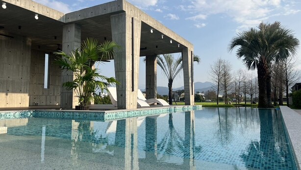 A modern building with a pool, concrete pillars, and palm trees. - 135 B&B (Dongshan)