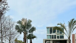 A modern two-story building with a glass facade, a small pond in front, and palm trees. - 135 B&B (Dongshan)