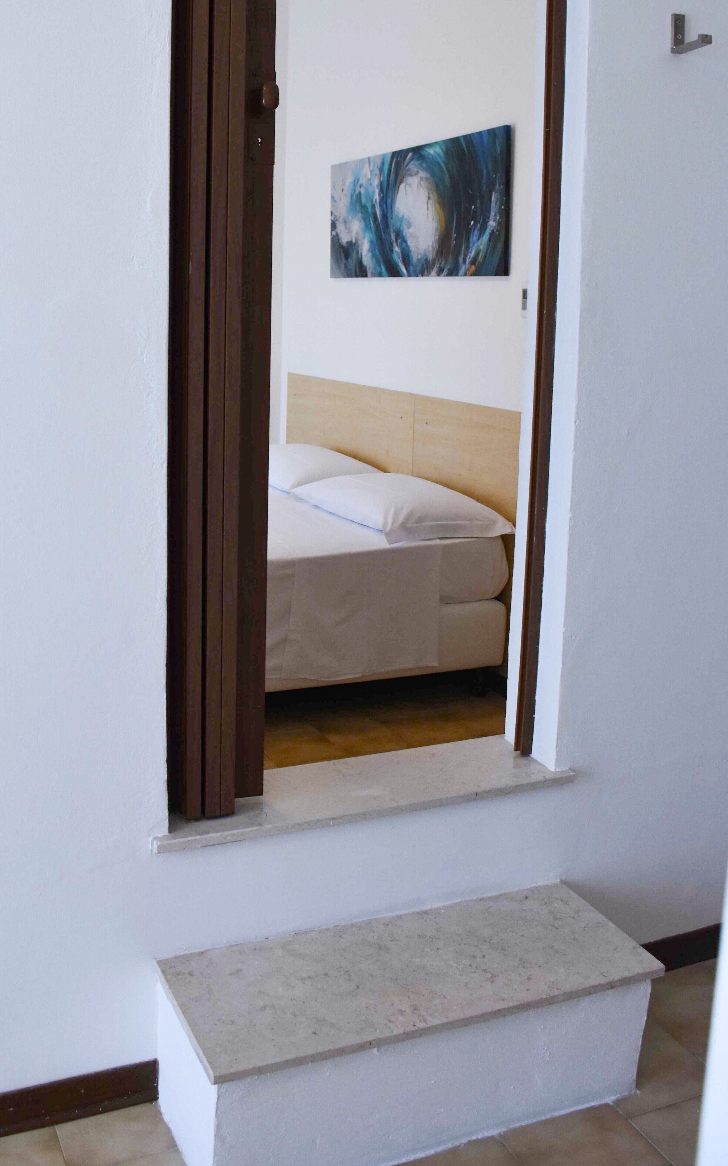 Un dormitori amb un llit, un capçal i un quadre a la paret.