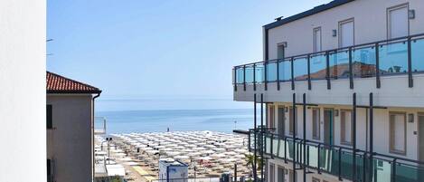 A multi-story building with a balcony overlooking a beach.