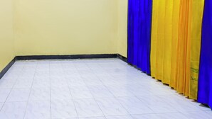 A room with a tiled floor, a yellow wall, and a row of blue and yellow curtains. - Hotel O Lestari Homestay (Kotaraja)