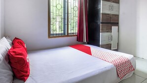 A single bed with white bedding and red accents, a window with metal bars, and a radiator on the wall. - Hotel O Lestari Homestay (Kotaraja)