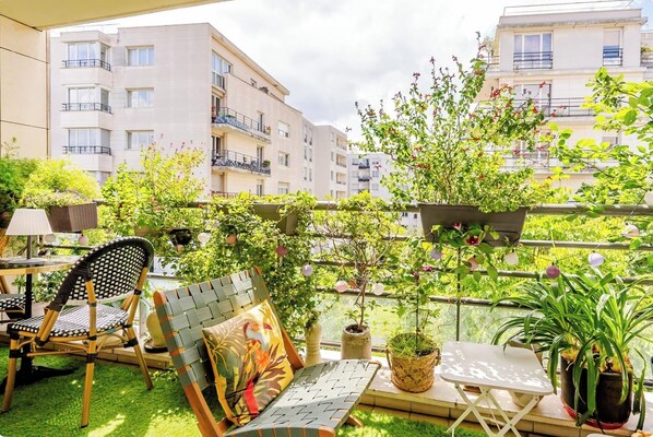 A balcony with a wicker chair, a small table, and potted plants. - Large Two-bedroom Flat to Rent in Paris,100m From Beautiful Buttes Chaumont Parc (Paris)
