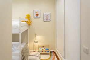 A child's bunk bed with a yellow toy, a small bedside table with books, and two framed pictures on the wall. - Ideal for 6px, modern and cosy (Faro)