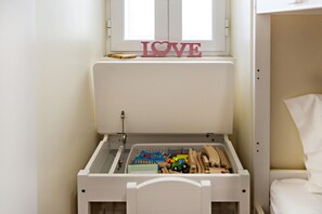 Uma área de recreação infantil com um armário cheio de brinquedos e uma janela com a inscrição 'LOVE'.