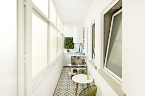 A narrow, brightly lit corridor with large windows, a small kitchenette with a stove and cabinets, and a green plant in the background. - Ideal for 6px, modern and cosy (Faro)