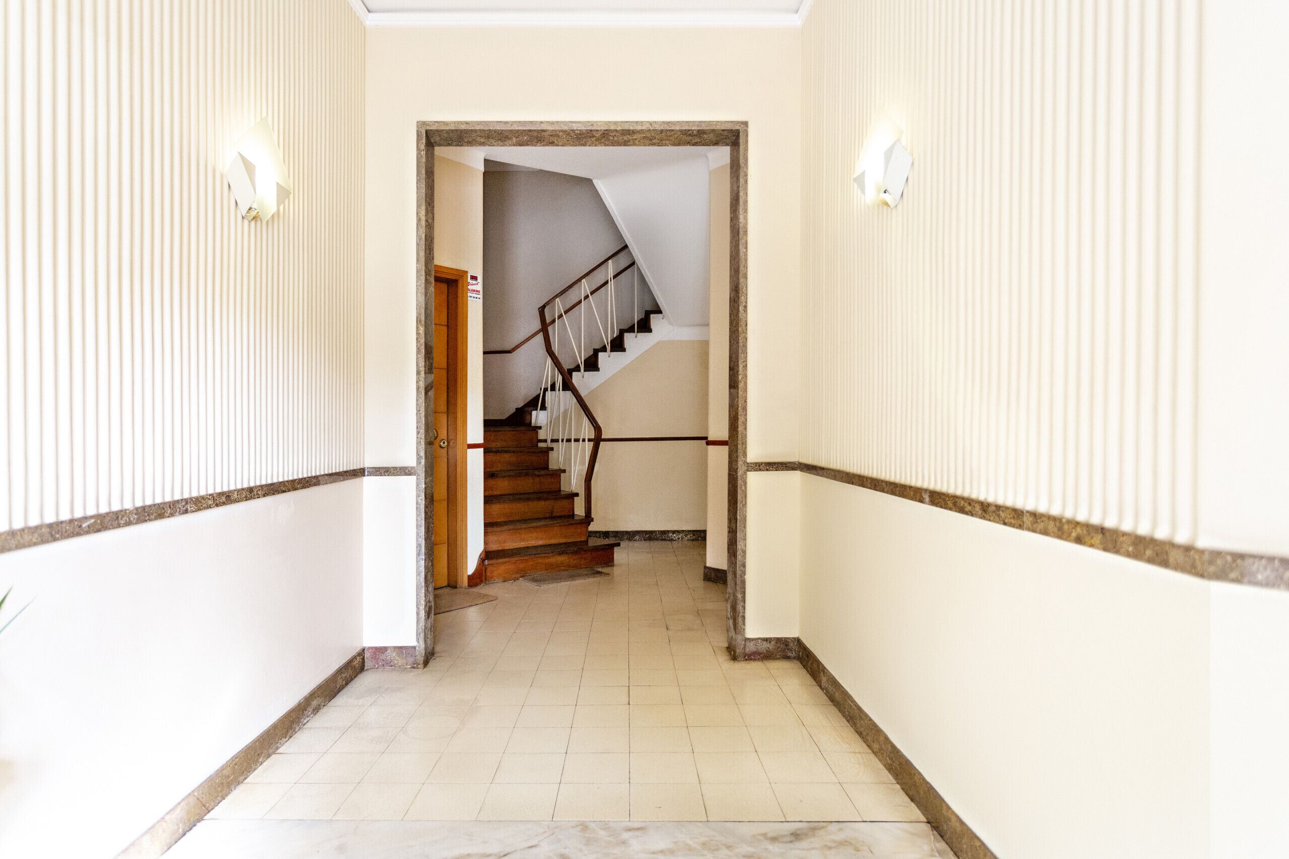 A hallway with a wooden staircase leading to an upper floor.
