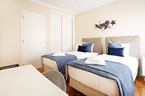 A hotel room with two beds, a desk, and a chair.