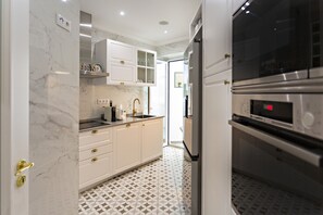 A modern kitchen with white cabinetry, a marble backsplash, and a patterned floor. - Ideal for 6px, modern and cosy (Faro)